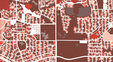 An aerial view of a residential neighborhood with plots of land highlighted in different shades of red