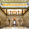 A university foyer with rows of arches divided by columns and statuary in neutral shades warmly lit by hidden lighting