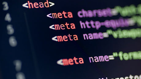 Фотография крупным планом компьютерного кода, написанного разноцветным шрифтом на черном экране