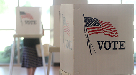 Multiple voting booths with American flags on their sides at a polling place 