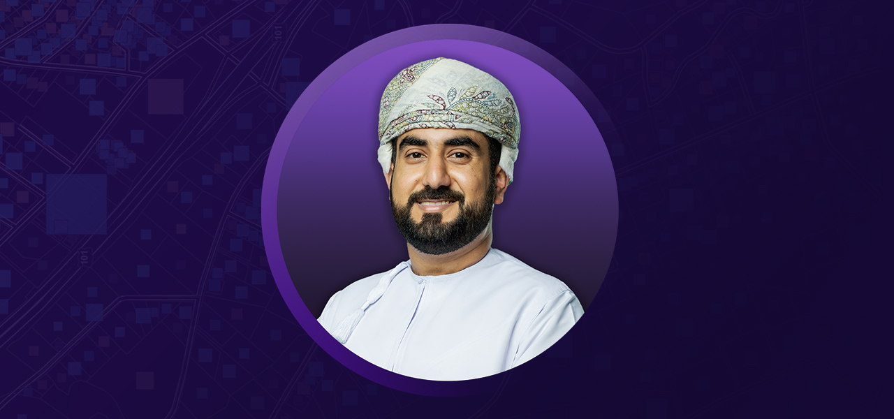 Mohammed Al-Maktoumi wearing a tunic and turban and smiling overlaid on a purple background 