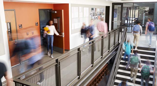 近代的な高校の校舎内で、階段を上ったり廊下を歩いたりしている生徒たち