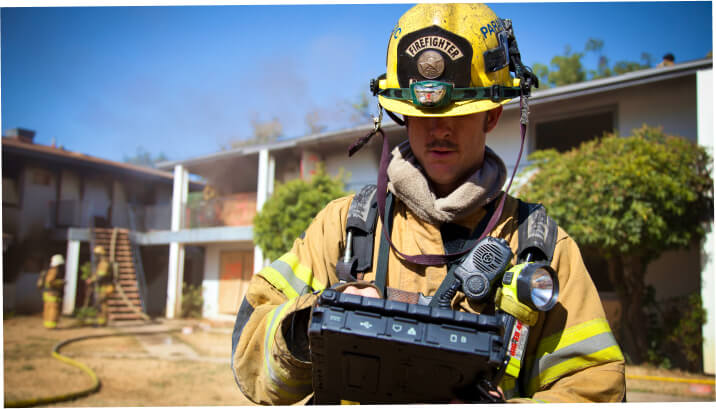Firefighter using a tablet at the scene of a fire to gather and share information