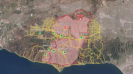 A contour map displaying the burn area and roads surrounding the Woolsey fire in pink and yellow on a green and tan background, with an interactive play button over the image to start the video