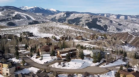 A residential community at the foot of a mountain range covered in snow