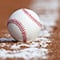 Close-up of a baseball resting on the foul line of a baseball diamond