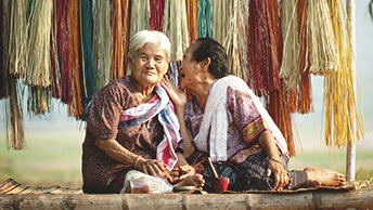 Due donne sedute all'aperto mentre una parla all'altra