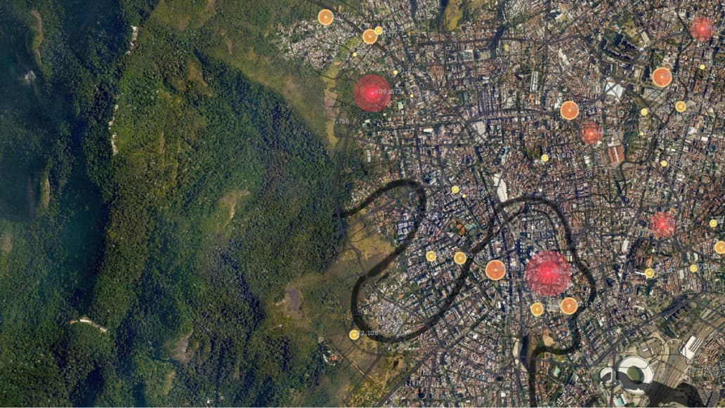 An aerial image of a sprawling city with borders meeting a densely wooded forest, scattered with yellow and red map points