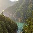 A small body of blue water surrounded by mountains with dense pine tree forests 