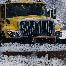 A snowplow on a residential street while it snows