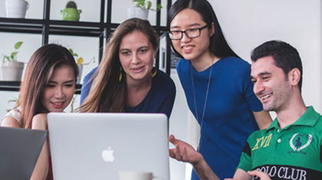 Group of four colleagues looking at laptop screen