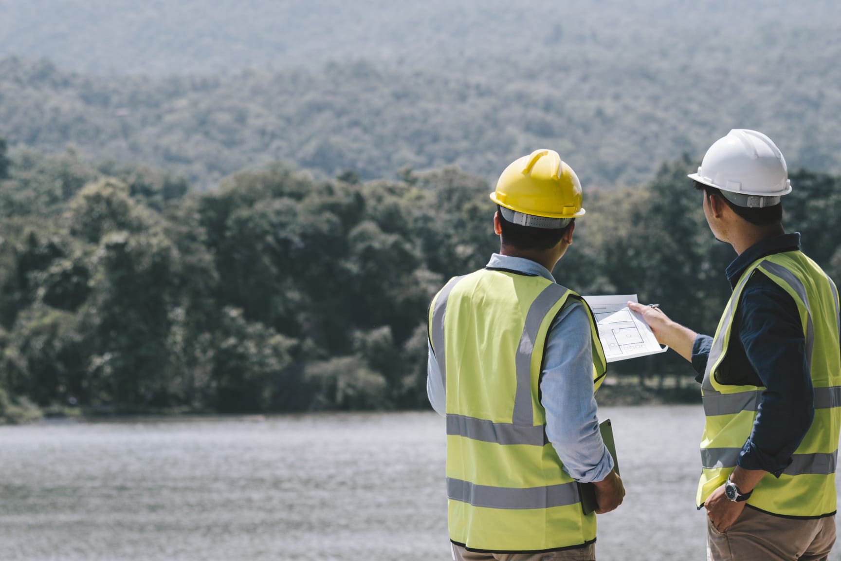 Two young maintenance engineer man working with blueprint on the mountain, Environmental engineering concept.