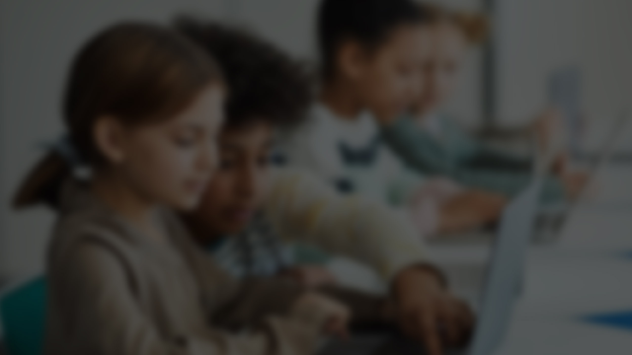 Young students on a laptop sitting at a table in a classroom. 