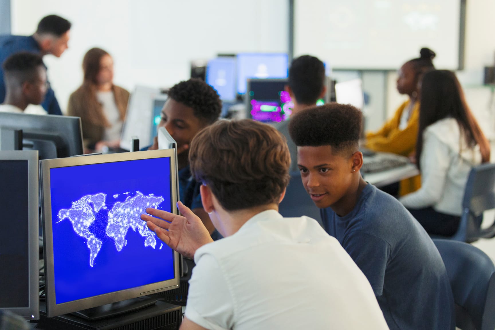 High School students in a computer lab looking at a world map on a computer. 