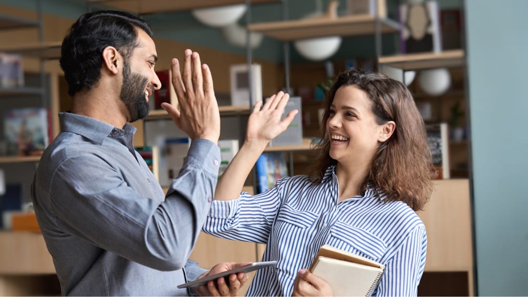 Image of two people happy people and they are doing a high five hand in the air.