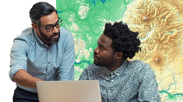 Два человека обсуждают карту на ноутбуке, а один из них указывает на экран ноутбука и фон карты