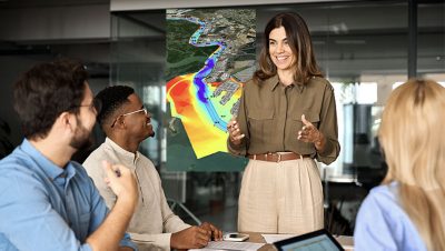 A group of four people gathered around a table in a conference room having a discussion, with a large map displayed on the wall behind them